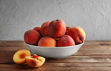 Fototapeta na wymiar Bowl with fresh peaches on wooden table