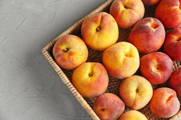 Basket with fresh peaches on light table