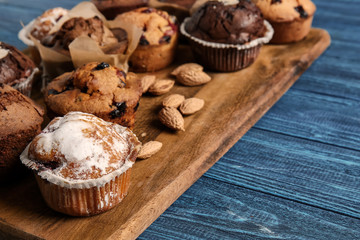Board with tasty muffins on wooden table