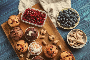 Board with tasty muffins and berries on wooden table