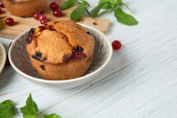 Plate with tasty cranberry muffin on white wooden table