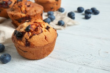 Tasty blueberry muffins on white wooden table