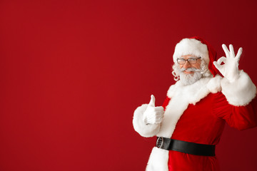 Portrait of Santa Claus showing thumb-up and OK gesture on color background