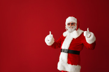 Portrait of cool Santa Claus showing thumb-up on color background
