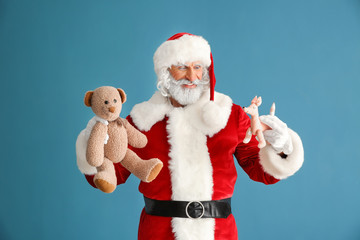 Portrait of Santa Claus with toys on color background
