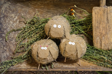 toy sheep made of straw and cloth stand on mown grass