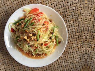 Thai cusine somtum or spicy papaya salad food dish on craft wood table background.