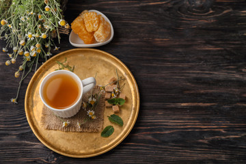Cup of delicious camomile tea and honeycombs on wooden table