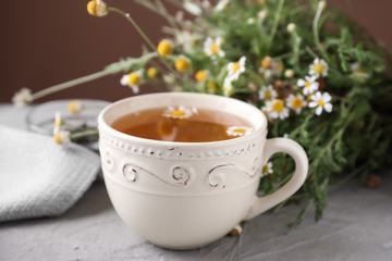 Obraz na płótnie Canvas Cup of delicious camomile tea on light table