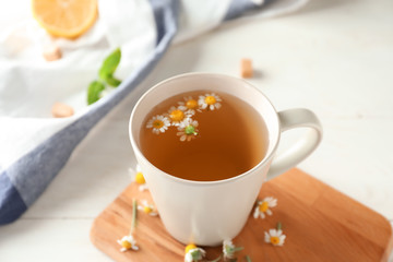 Cup of delicious camomile tea on table