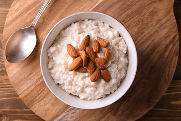 Delicious rice pudding with almonds in bowl on wooden board