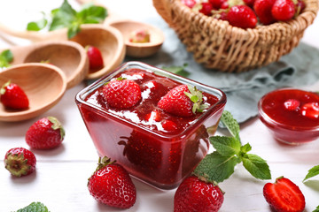 Bowl with delicious strawberry jam on white wooden table