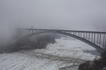 Niagara falls International Rainbow bridge in the winter with foggy wheather and frozen Niagara river
