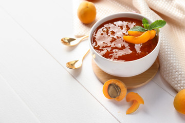 Bowl with sweet apricot jam on white table