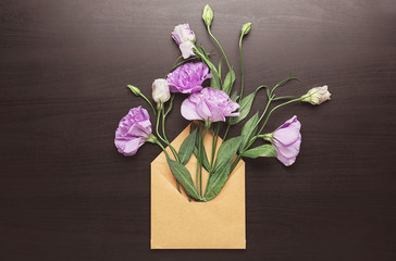 Open mail envelope with eustoma flowers on dark background