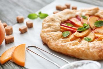 Parchment with delicious peach galette on table