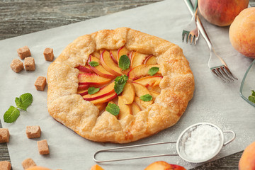 Parchment with delicious peach galette on table