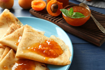 Tasty thin pancakes with apricot jam on plate