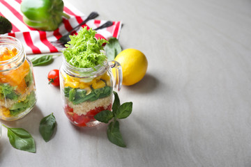 Delicious vegetable salads in mason jars on grey table