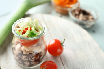 Delicious vegetable salad with chicken in mason jar on wooden board