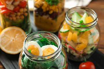 Delicious vegetable salads with egg in mason jars, closeup
