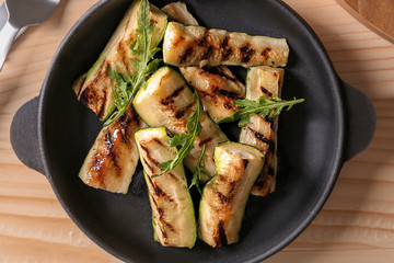 Pan with tasty grilled zucchini on wooden table