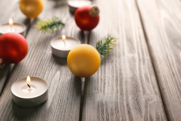 Christmas balls and burning candles on wooden background