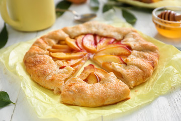Parchment with delicious peach galette on white table
