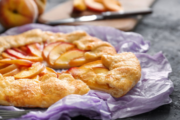 Parchment with delicious peach galette on dark table, closeup