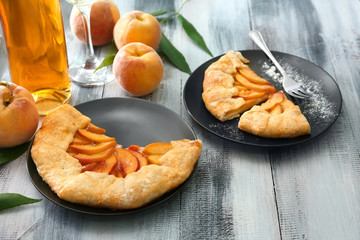 Plates with delicious peach galette on wooden table