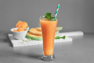 Glass with delicious melon smoothie on grey table