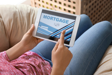 Woman using tablet computer to pay mortgage loan online at home