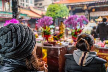 Fototapeta premium Unrecognizable asian woman holding an incense stick praying at Lungshan Buddhist Temple in Taipei Taiwan