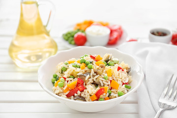 Plate with tasty boiled rice and vegetables on white table