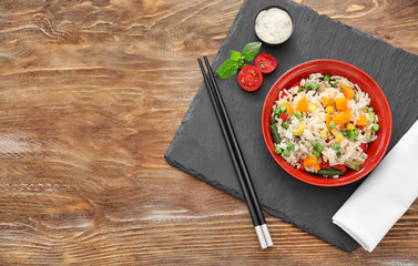 Tasty boiled rice with vegetables on slate plate