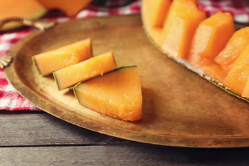 Tray with cut ripe melon on table, closeup