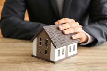 Real estate agent with house model at wooden table