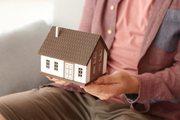Man holding house model, closeup. Mortgage concept