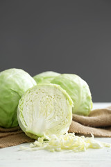 Whole and sliced cabbage on white table