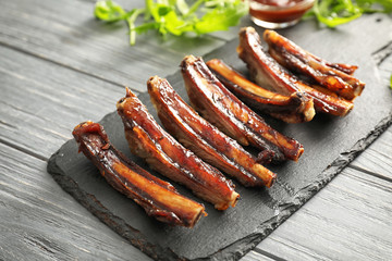 Slate plate with delicious grilled ribs on wooden table