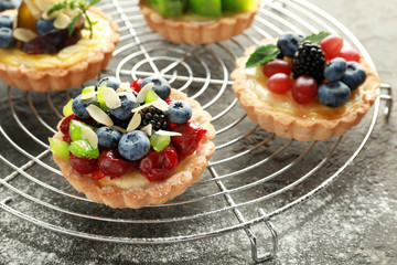 Delicious tarts with fruits and berries on cooling rack