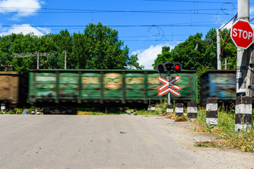 Railroad crossing sign and blinking semaphore in front of the railroad crossing. Blurred motion of...