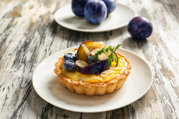 Delicious tart with plum and blueberries on wooden table