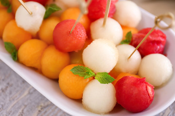 Plate with tasty melon balls on table, closeup