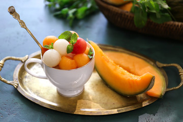Cup with tasty melon balls on table