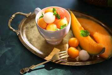 Cup with tasty melon balls on table