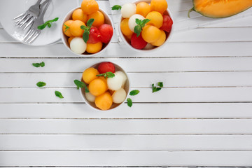 Bowls with tasty melon dessert on white wooden table