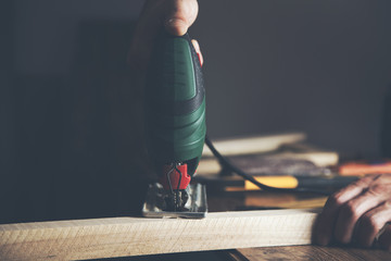 Men's hands cutting the board with electric jig saws