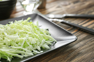 Plate with cut cabbage on wooden table, closeup