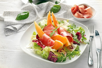 Delicious melon with prosciutto and herbs on plate